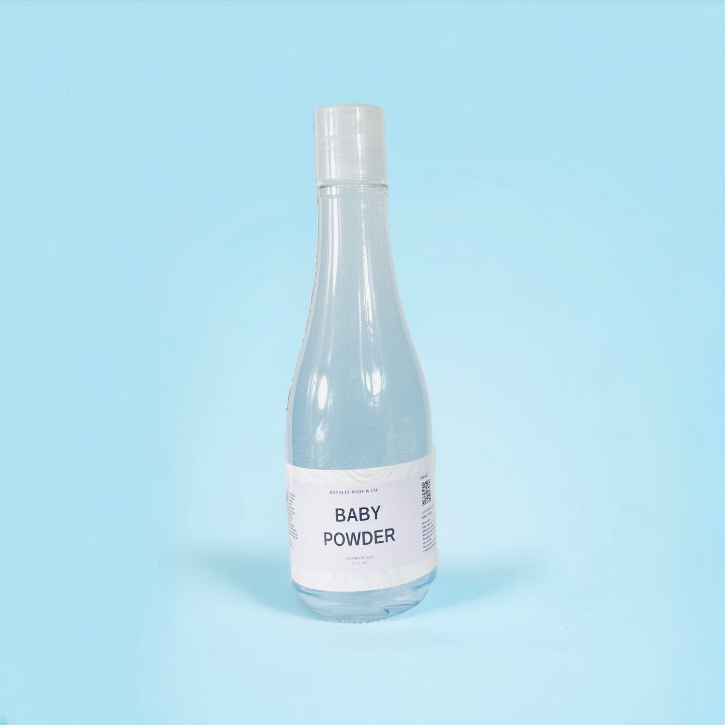 A transparent plastic bottle with a white Baby Powder Shower Gel label stands against a light blue background. Reminiscent of soothing cedarwood elements, it is sealed with a white cap, containing shower gel resembling white or light-colored powder.