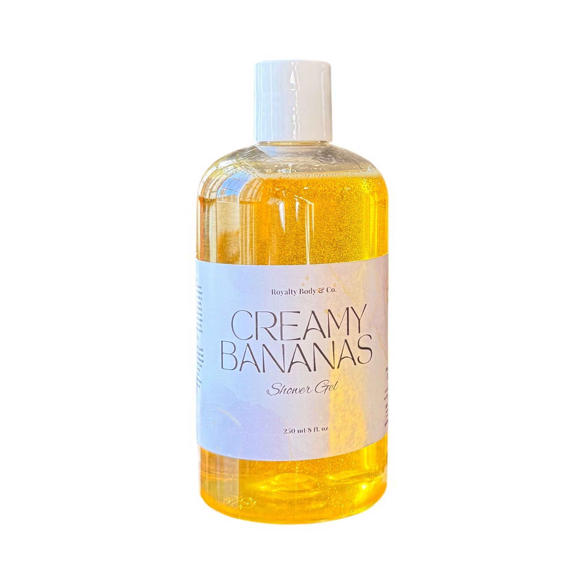 A clear bottle of Iced Cinnamon Buns Shower Gel by Royalty Body & Co. showcases a rich gel infused with vegetable glycerin for added moisture. The bottle is topped with a white cap and features a large, light-colored label detailing the products nourishing benefits.